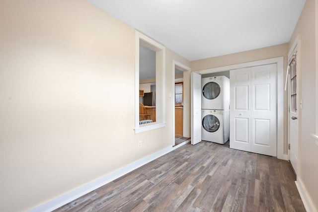 washroom with stacked washer and dryer and wood-type flooring