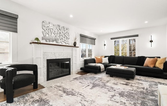 living area with recessed lighting, a premium fireplace, and wood finished floors