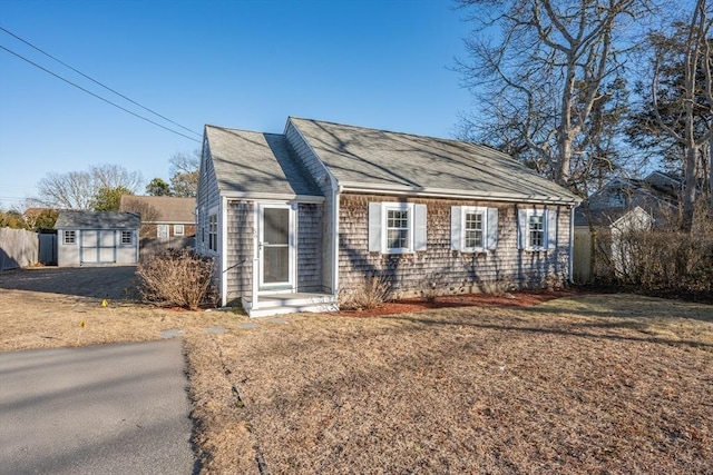 56 Baxter Ave, Yarmouth, MA 02673 - view of front facade with fence, roof with shingles, an outdoor structure, and a storage shed