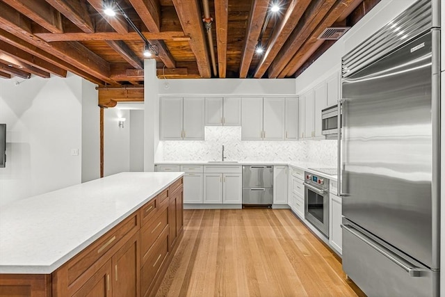 343 Commercial St Unit 212, Boston, MA 02109 - kitchen featuring built in appliances, light wood-type flooring, light countertops, tasteful backsplash, and wooden ceiling with exposed beams