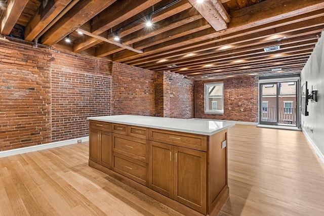 343 Commercial St Unit 212, Boston, MA 02109 - kitchen featuring brick wall, light wood finished floors, light countertops, brown cabinets, and a center island