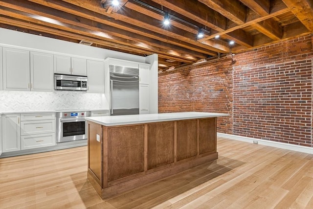 343 Commercial St Unit 212, Boston, MA 02109 - kitchen with appliances with stainless steel finishes, light countertops, a center island, decorative backsplash, and light wood-type flooring
