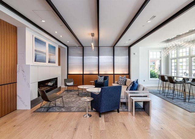 living room with a tiled fireplace, a notable chandelier, and light hardwood / wood-style flooring