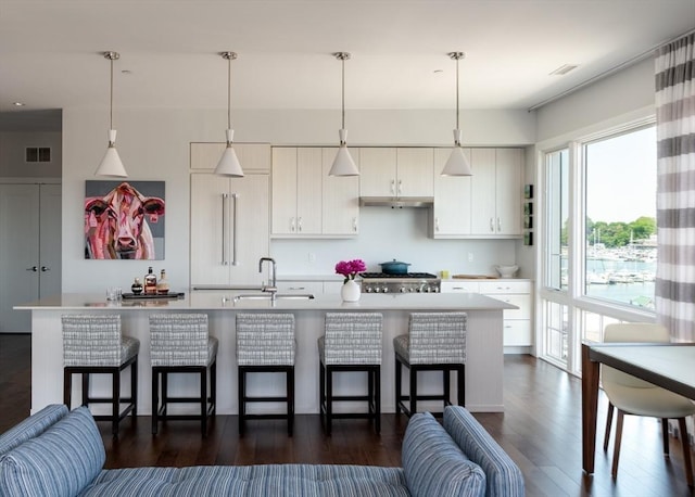 kitchen featuring sink, hanging light fixtures, white cabinetry, and a kitchen breakfast bar