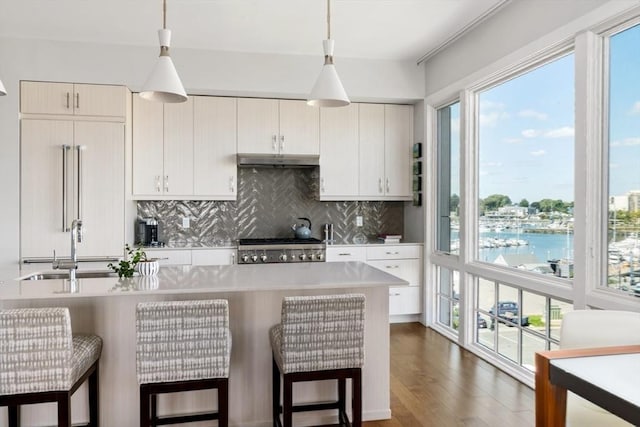 kitchen featuring sink, a water view, stove, decorative backsplash, and pendant lighting