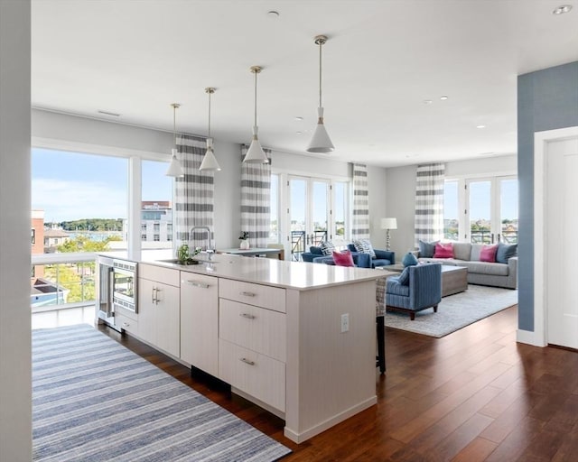 kitchen with sink, white cabinets, decorative light fixtures, white dishwasher, and a center island with sink