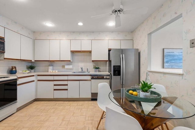 kitchen featuring stainless steel appliances, light parquet floors, white cabinets, and sink