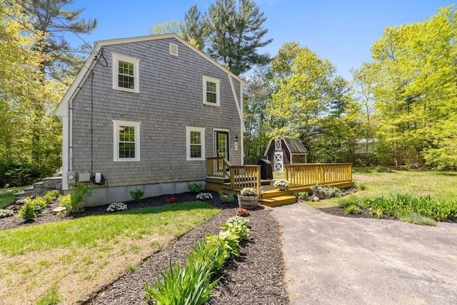 62 Bianca Rd, Duxbury, MA 02332 - view of front of house featuring a wooden deck, a front lawn, a gambrel roof, and an outbuilding