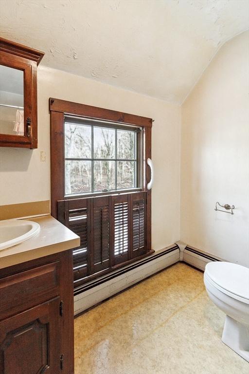 bathroom featuring vanity, vaulted ceiling, a baseboard radiator, and toilet