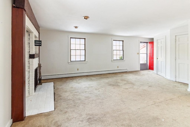 unfurnished living room featuring a brick fireplace, carpet, and a baseboard heating unit