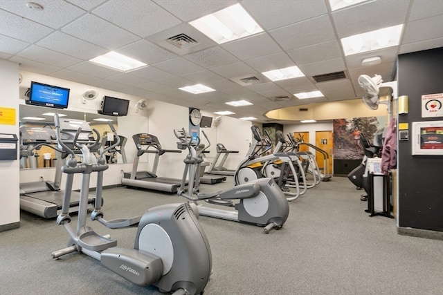 gym with a paneled ceiling and carpet flooring