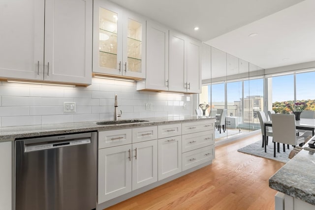 kitchen with stainless steel dishwasher, sink, white cabinets, and light wood-type flooring