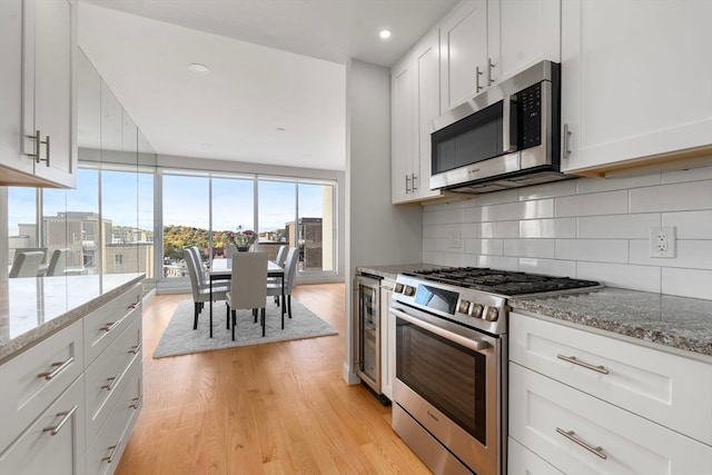 kitchen featuring light hardwood / wood-style floors, white cabinetry, stainless steel appliances, and light stone counters