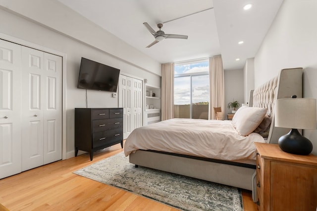 bedroom with multiple closets, wood-type flooring, and ceiling fan