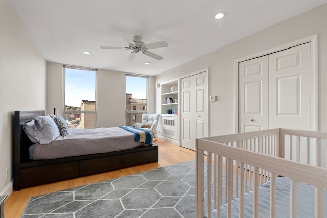 bedroom with ceiling fan, hardwood / wood-style flooring, and multiple closets