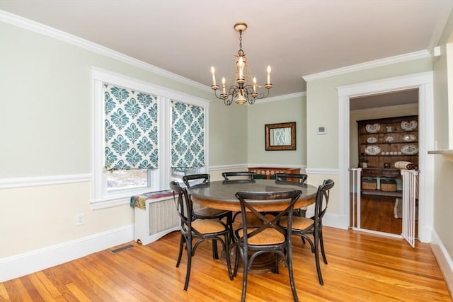 dining area with radiator, light hardwood / wood-style flooring, ornamental molding, and a notable chandelier