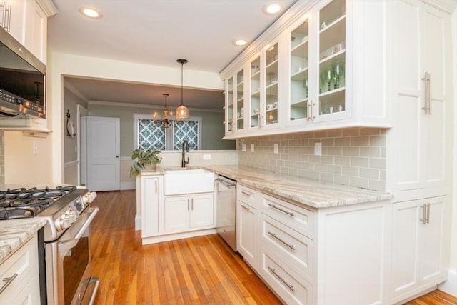 kitchen with white cabinetry, kitchen peninsula, stainless steel appliances, pendant lighting, and sink