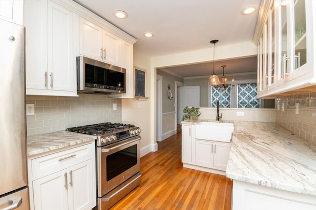 kitchen featuring backsplash, sink, white cabinetry, light stone countertops, and appliances with stainless steel finishes