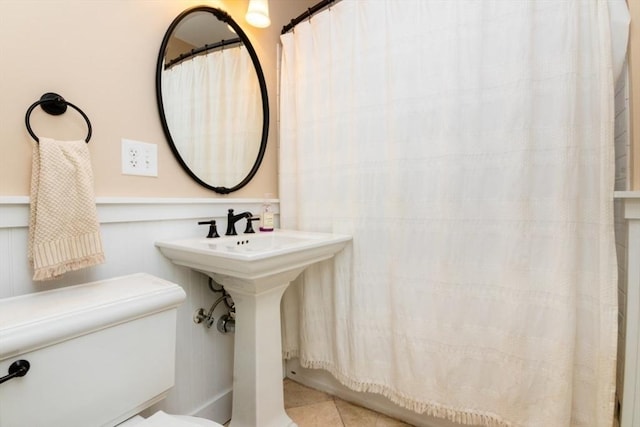 bathroom featuring toilet, a shower with curtain, and tile patterned floors