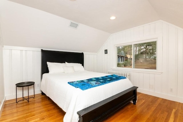 bedroom featuring radiator, vaulted ceiling, and hardwood / wood-style flooring