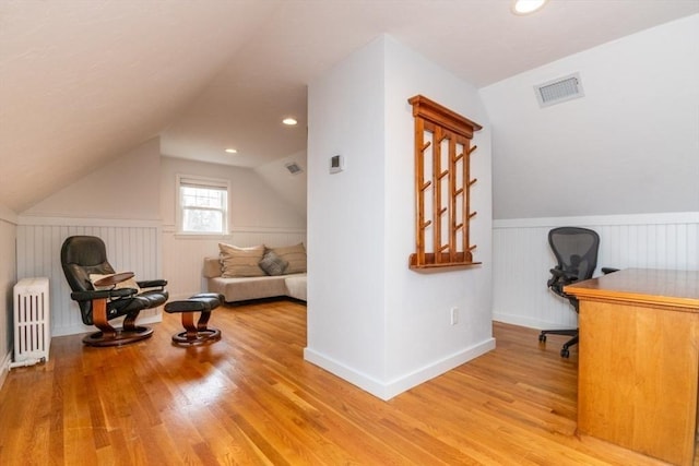 home office featuring vaulted ceiling, light hardwood / wood-style flooring, and radiator heating unit