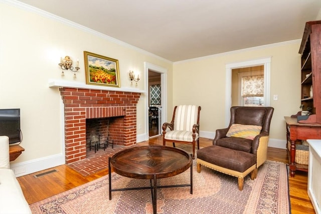 sitting room with light wood-type flooring, a brick fireplace, and crown molding