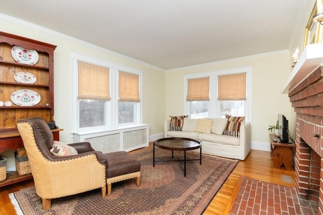 living room with ornamental molding, a fireplace, hardwood / wood-style floors, and radiator heating unit