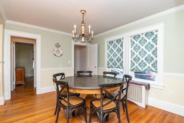 dining space with light wood-type flooring, a notable chandelier, and crown molding