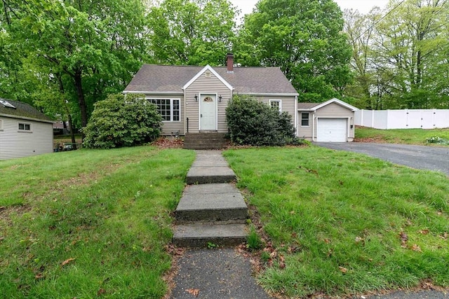 view of front facade featuring a chimney, a garage, a front lawn, and fence