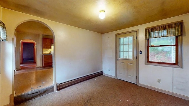 doorway to outside with baseboards, arched walkways, and carpet floors