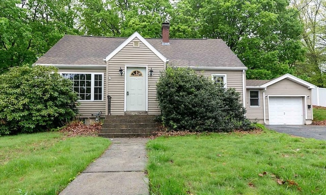 view of front of house featuring an attached garage, a front lawn, a chimney, and driveway
