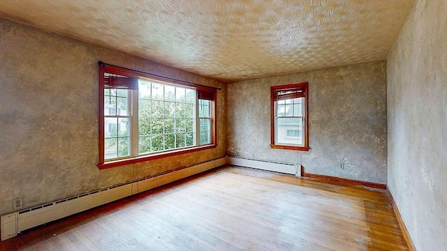 spare room with a baseboard radiator, baseboards, and hardwood / wood-style floors