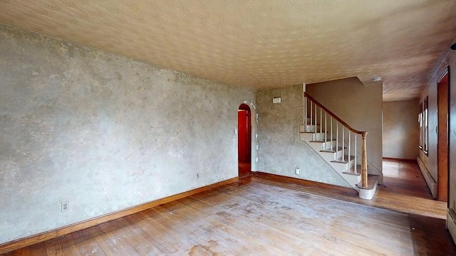 interior space with stairway, hardwood / wood-style flooring, arched walkways, and baseboards