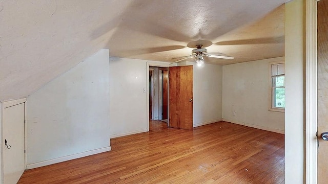 bonus room with baseboards, light wood finished floors, ceiling fan, and vaulted ceiling