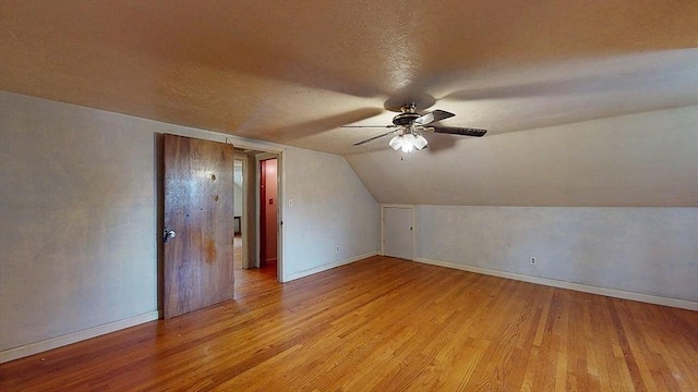 additional living space with baseboards, light wood-style floors, ceiling fan, and lofted ceiling