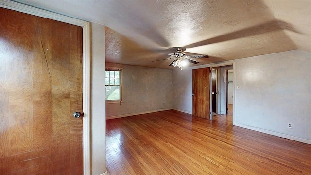 spare room with light wood finished floors, a textured ceiling, baseboards, and ceiling fan