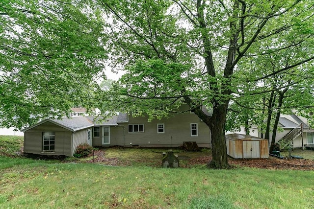 back of house with a yard, an outbuilding, and a shed