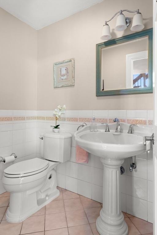 half bathroom featuring tile patterned flooring, wainscoting, tile walls, and toilet
