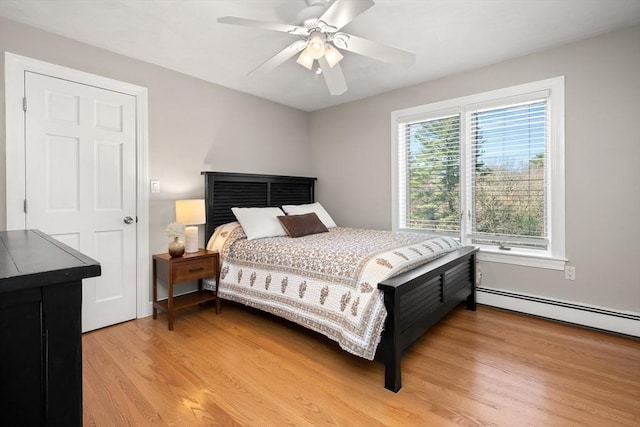 bedroom featuring light wood-type flooring, a baseboard heating unit, and a ceiling fan