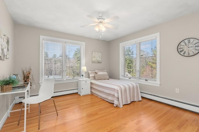 bedroom with light wood-style flooring, multiple windows, and baseboard heating