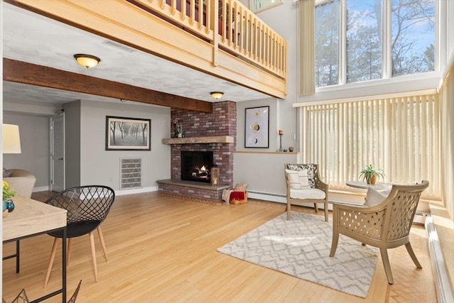 living room featuring visible vents, a brick fireplace, wood finished floors, and baseboards