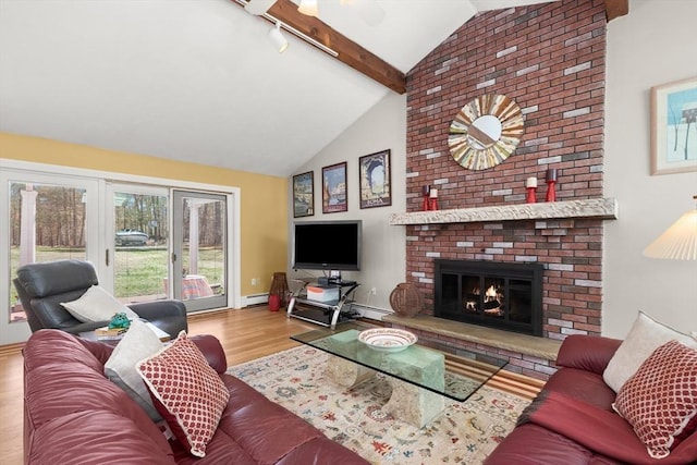 living area featuring baseboards, baseboard heating, a fireplace, wood finished floors, and high vaulted ceiling