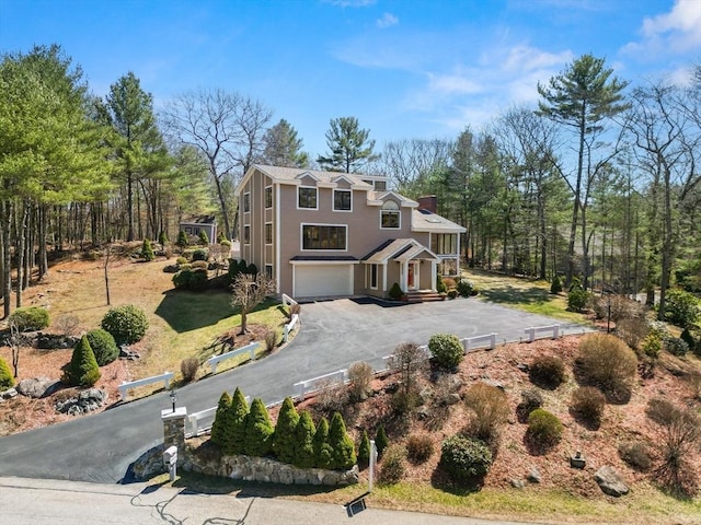 view of front of property with driveway, a garage, and a chimney