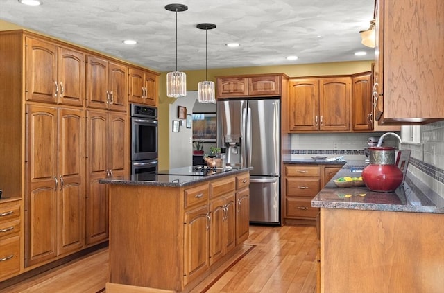 kitchen featuring a center island, light wood-style flooring, brown cabinets, and appliances with stainless steel finishes