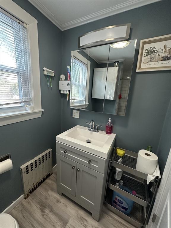 26 Woodman St, Lynn, MA 01905 - bathroom with radiator heating unit, vanity, wood finished floors, crown molding, and baseboards