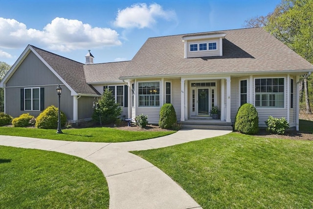 view of front facade with a shingled roof and a front lawn