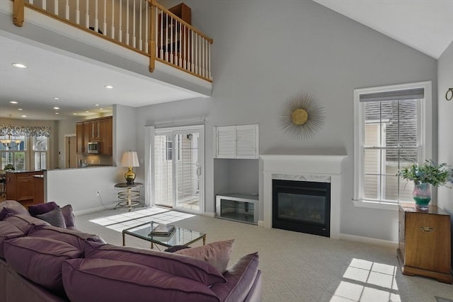 living area with baseboards, a wealth of natural light, light carpet, and high vaulted ceiling
