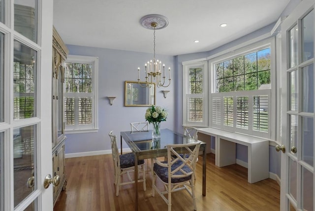 dining space featuring baseboards, a notable chandelier, plenty of natural light, and wood finished floors