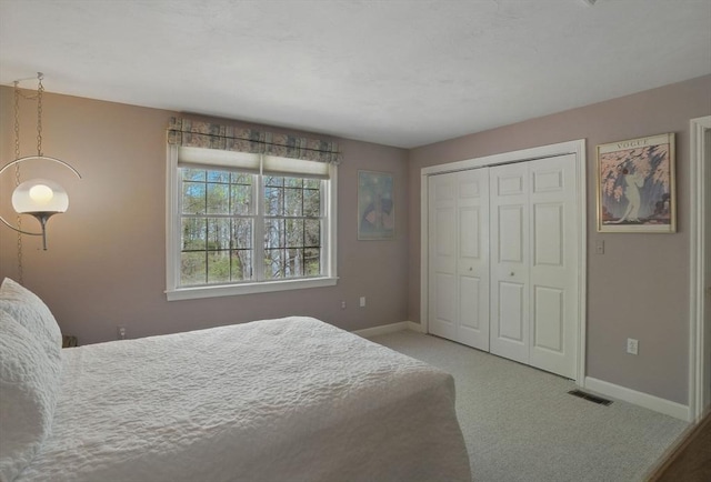 carpeted bedroom featuring a closet, visible vents, and baseboards
