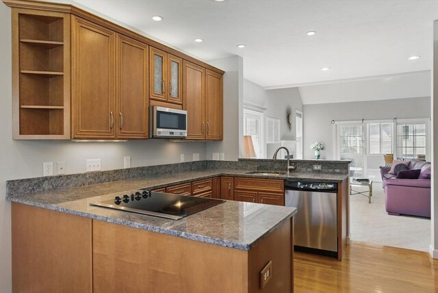 kitchen featuring open shelves, stainless steel appliances, a peninsula, and a sink